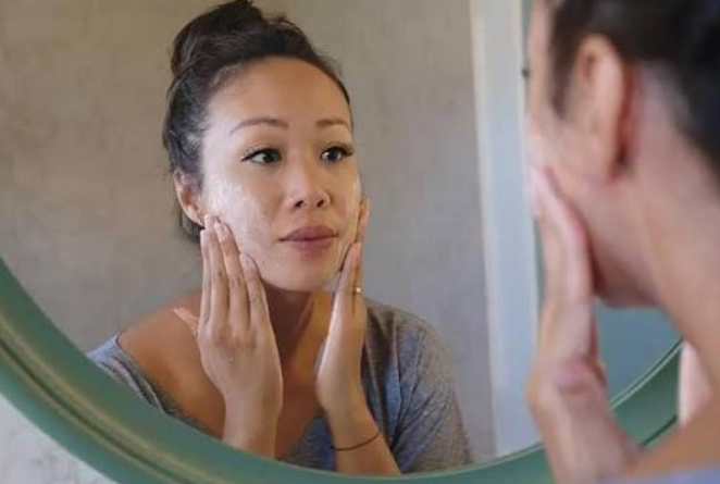 Woman applying skincare in mirror